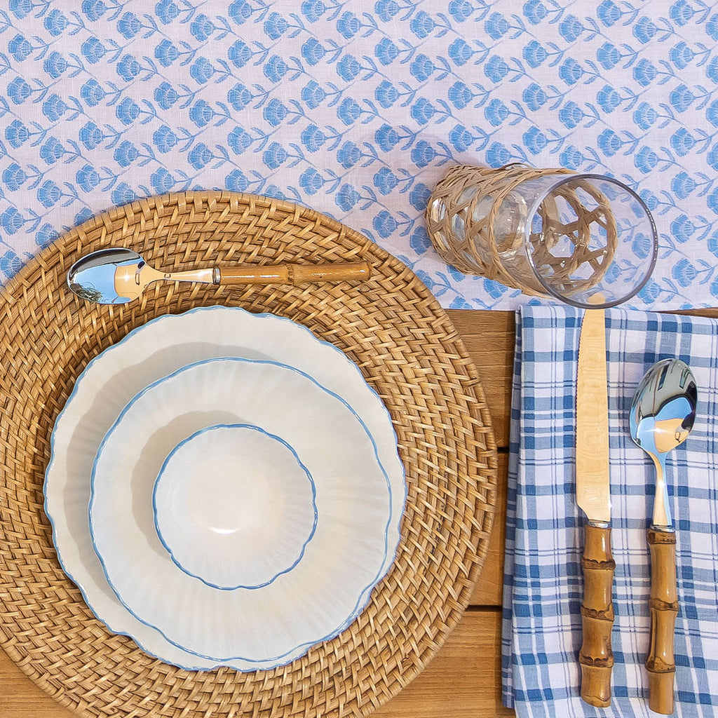 A vibrant Del Mar table runner adorns an outdoor dining table. The runner features a captivating floral design, accompanied by the Coronado napkin in blue. 