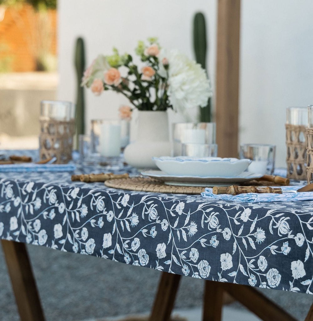 A beautiful dinner arrangement sitting atop the Montecito Table Runner. Deep blue and white floral hues lay beneath floral arrangements, plates, and cocktails.